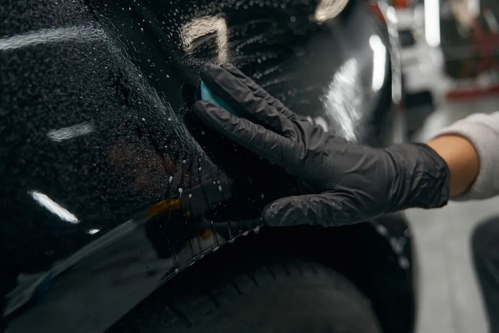 Skilled worker removing contaminants from motor vehicle clear coat