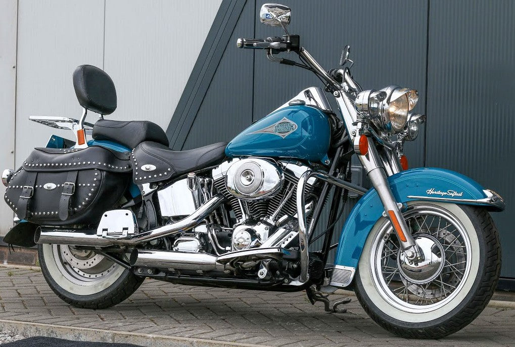 Blue motorcycle parked on a paved surface with a gray wall in the background