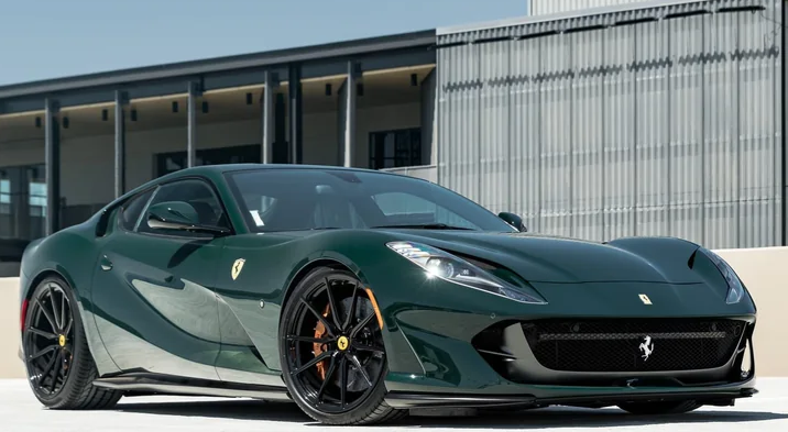 A green Ferrari sports car parked in front of a modern building.